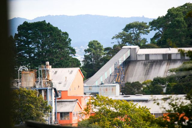 A factory nestled in a forest with hills in the background, showcasing industrial harmony with nature.